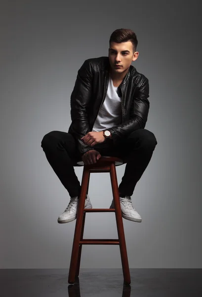 Sensual young man posing seated on stool in studio — Stock fotografie