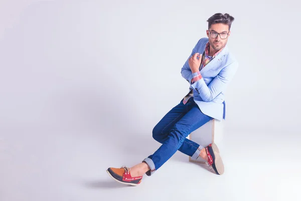 Man wearing glasses posing seated hith hands and legs crossed — 图库照片