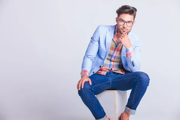 Sensual hombre casual con gafas y jeans sentados —  Fotos de Stock