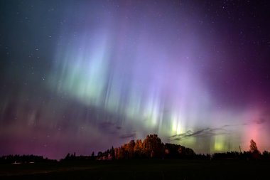 Kuzey ışıklarının bulutlu gökyüzünde dans edişinin manzarası