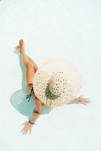 Frau mit weißem Hut sitzt am Pool — Stockfoto