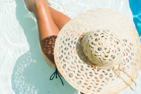 Mulher de chapéu branco sentada na piscina — Fotografia de Stock