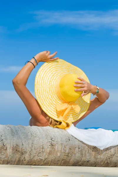 Vrouw in bikini dragen van een gele hoed op tropisch strand — Stockfoto