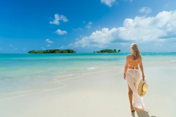 Kvinna med sarong promenerar på stranden — Stockfoto