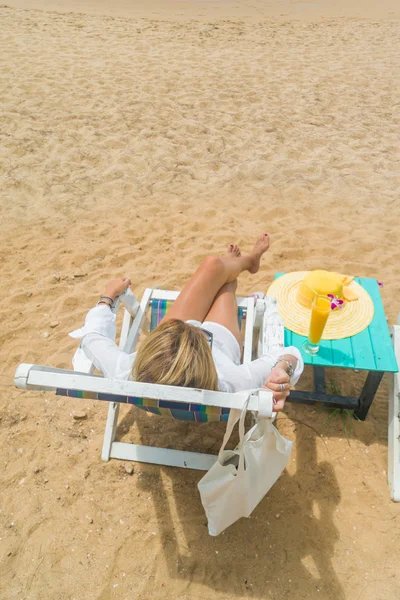 Donna seduta su una sedia a sdraio rilassarsi in spiaggia — Foto Stock