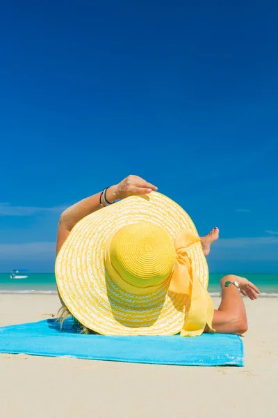 Kvinna i bikini bär en gul hatt på tropical beach — Stockfoto