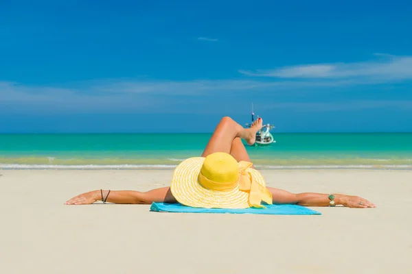 Kvinna i bikini bär en gul hatt på tropical beach — Stockfoto