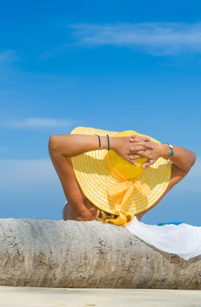 Vrouw in bikini dragen van een gele hoed op tropisch strand — Stockfoto