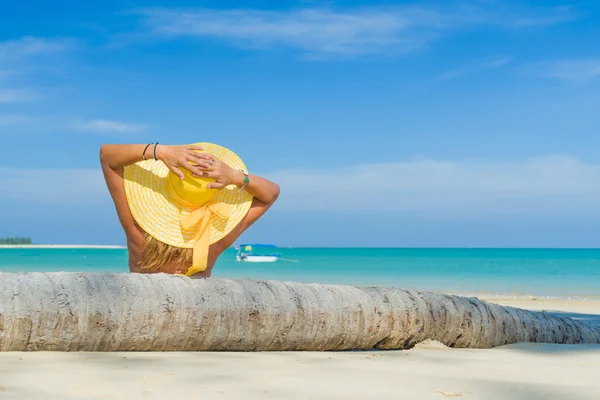 Kvinna i bikini bär en gul hatt på tropical beach — Stockfoto