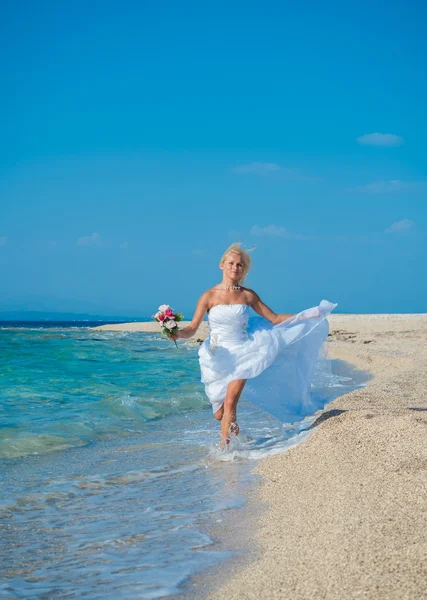 Schöne junge Braut zu Fuß am Strand — Stockfoto