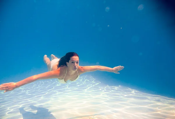 Mulher nadando debaixo d 'água em uma piscina — Fotografia de Stock