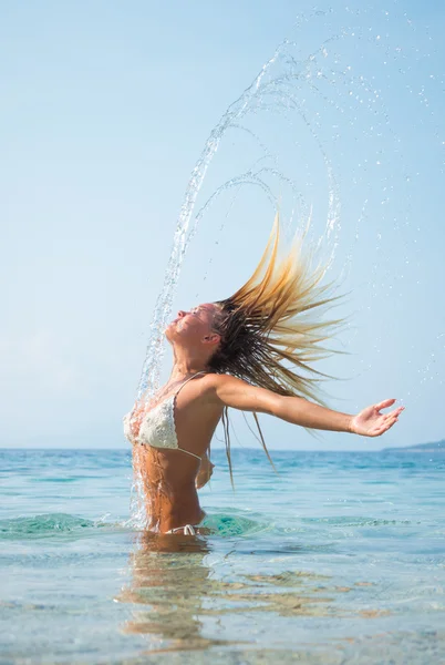 Frau im Wasser wedelt mit Haaren — Stockfoto