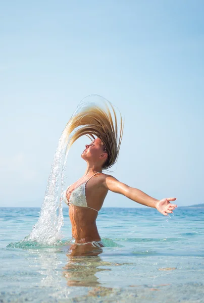 Frau im Wasser wedelt mit Haaren — Stockfoto