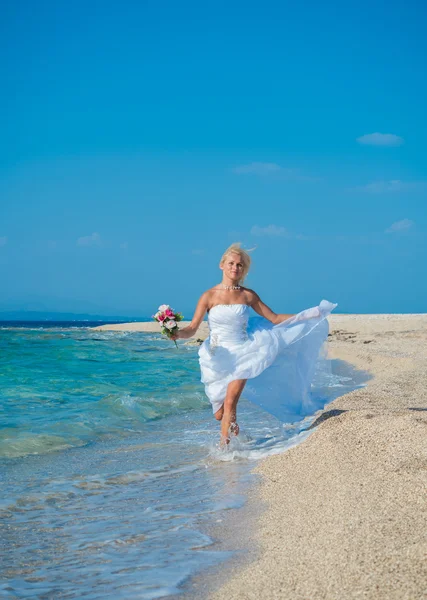 Belle jeune mariée marchant sur la plage — Photo