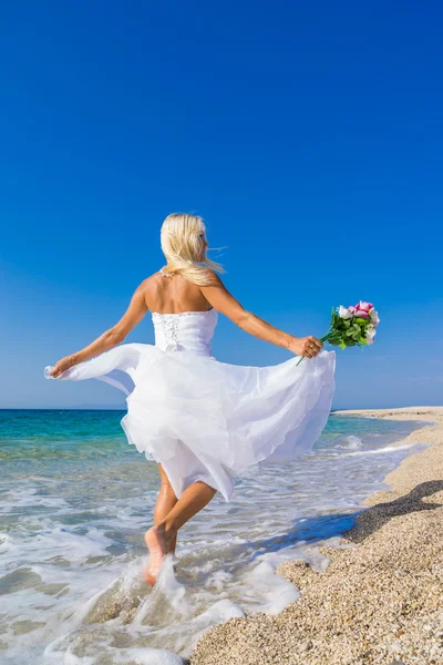 Beautiful young bride walking on the beach — Stock Photo, Image