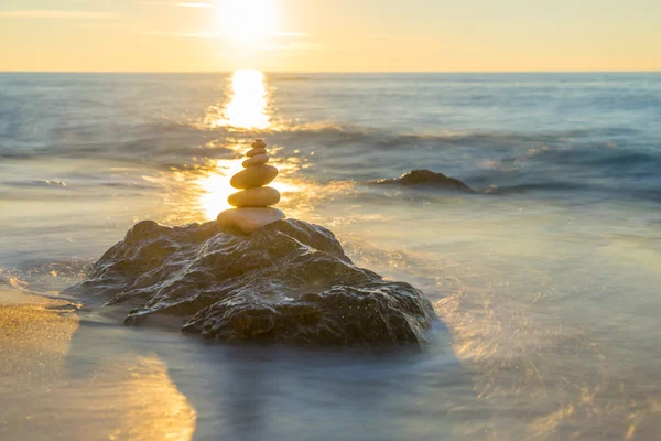 Pirámide de piedras sobre arena que simboliza zen, armonía, equilibrio. Océano — Foto de Stock