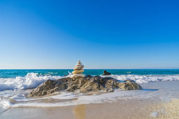 Pirámide de piedras sobre arena que simboliza zen, armonía, equilibrio. Océano — Foto de Stock