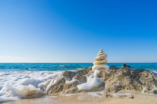 Pirámide de piedras sobre arena que simboliza zen, armonía, equilibrio. Océano — Foto de Stock