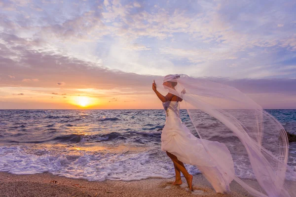 Sposa posa mostrando il suo abito da sposa sulla spiaggia — Foto Stock