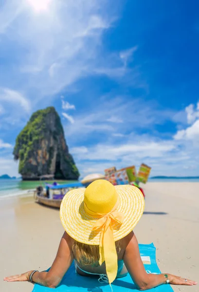 Jovem mulher vestindo um biquíni e chapéu de sol sentado na praia — Fotografia de Stock