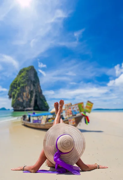 Ung kvinna som bär en bikini och solen hatt som sitter på stranden — Stockfoto