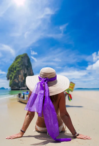 Jeune femme portant un bikini et un chapeau de soleil assis sur la plage — Photo