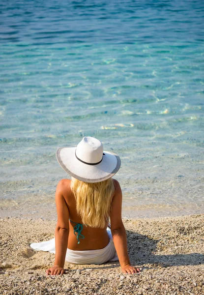 Wunderschöne Blondine im Bikini am Strand sitzend — Stockfoto