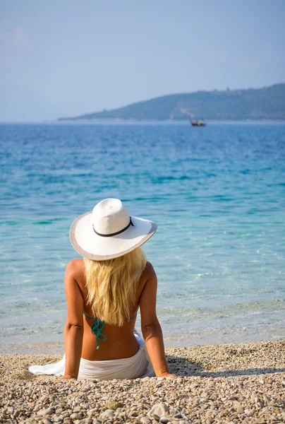 Wunderschöne Blondine im Bikini am Strand sitzend — Stockfoto