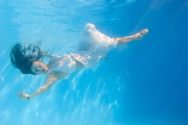 Yüzme havuzunda sualtı beyaz elbise giymiş kadın