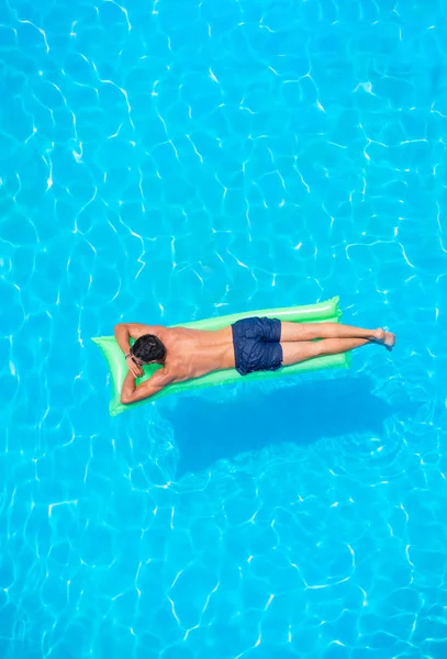 Mann entspannt sich auf Luftmatratze im Schwimmbad. — Stockfoto