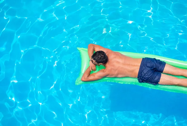 Muž na posteli vzduchu v bazénu relaxační. — Stock fotografie