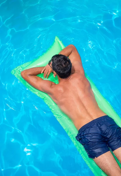 Ο άνθρωπος που είναι ξεκούραστη στο κρεβάτι αέρα στην πισίνα. — Φωτογραφία Αρχείου