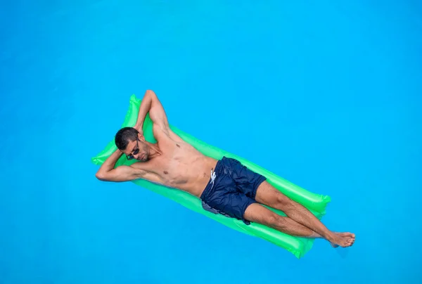 man relaxing on the air bed in the swimming pool.