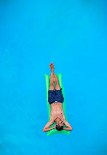 Mann entspannt sich auf Luftmatratze im Schwimmbad. — Stockfoto