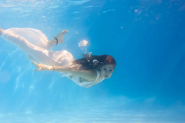 Frau in weißem Kleid unter Wasser im Schwimmbad — Stockfoto