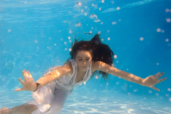 Žena v bílých šatech pod vodou v bazénu — Stock fotografie