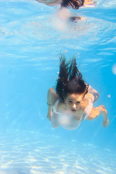 Woman in a white dress underwater in swimming pool Royalty Free Stock Images