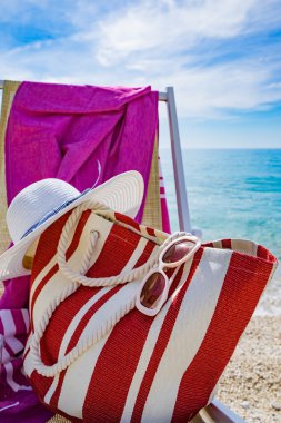 plaj şezlong, havlu, çanta, şapka ile 