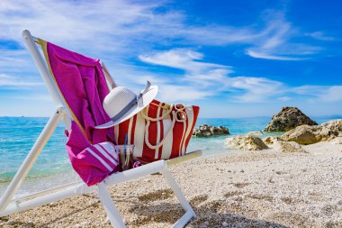 plaj şezlong, havlu, çanta, şapka ile 