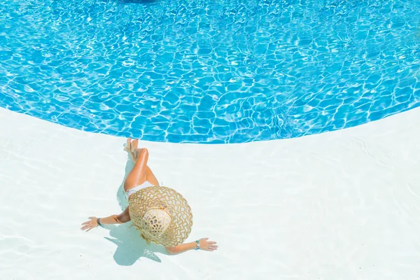 Schöne Frau mit Hut sitzt am Rande des Pools — Stockfoto