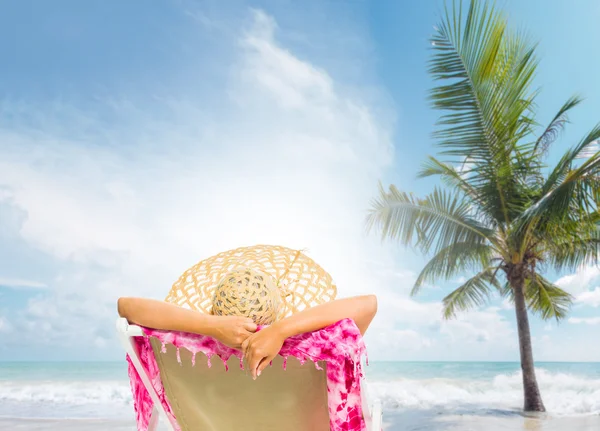Jovem mulher sentada em uma cama de sol na praia — Fotografia de Stock