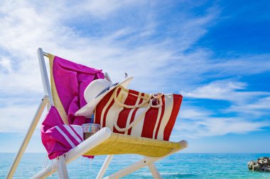 plaj şezlong, havlu, çanta, şapka ile 