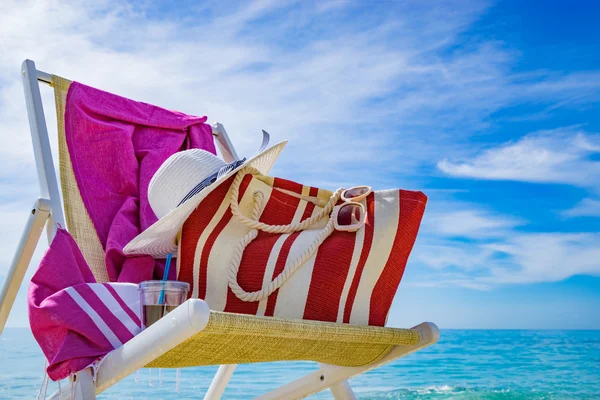 Beach with deck chair, towel, bag, hat — Stock Photo, Image