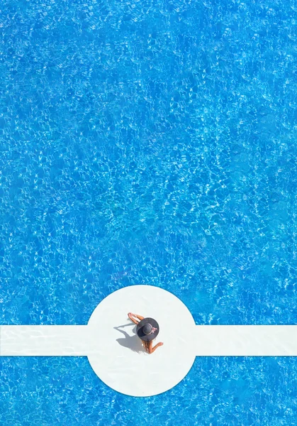 Woman in a hat sitting on the edge of the pool — Stock Photo, Image