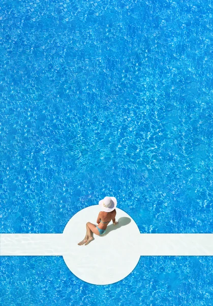 Mujer en un sombrero sentado en el borde de la piscina —  Fotos de Stock