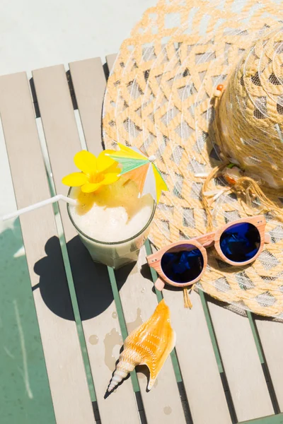 Плавательный стол с солнцезащитными очками, шляпой и свежим коктейлем — стоковое фото