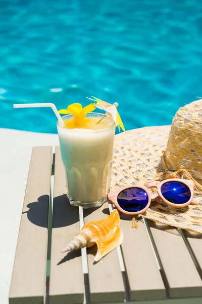 Swimming pool table with sunglasses, hat and fresh cocktail — Stock Photo, Image