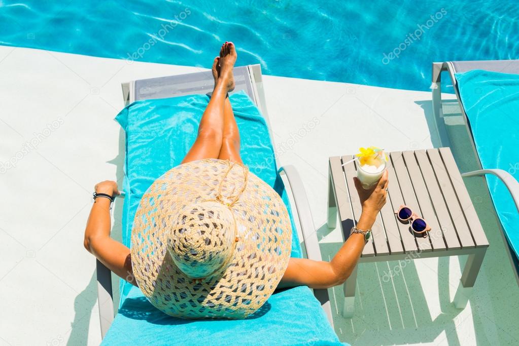 Woman at the poolside with pina colada cocktail
