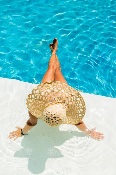 Vrouw met hoed bij het zwembad — Stockfoto