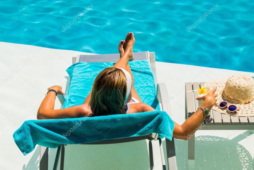 Woman at the poolside with pina colada cocktail
